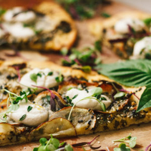 Vegan Potato and Pesto Pizza Topped with Crème Fraîche and Micro Greens