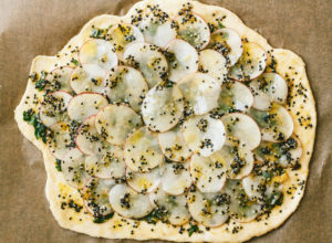 Vegan Potato and Pesto Pizza Topped with Crème Fraîche and Micro Greens