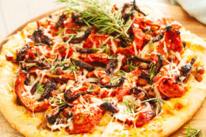 Roasted Red Pepper Vegan Chicken, Tofu Bacon, Mushroom, Sun Dried Tomato Pizza, and Fresh Rosemary Leaves with Herbed Crust