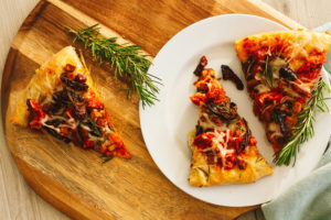 Roasted Red Pepper Vegan Chicken, Tofu Bacon, Mushroom, Sun Dried Tomato Pizza, and Fresh Rosemary Leaves with Herbed Crust