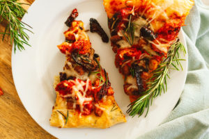 Roasted Red Pepper Vegan Chicken, Tofu Bacon, Mushroom, Sun Dried Tomato Pizza, and Fresh Rosemary Leaves with Herbed Crust