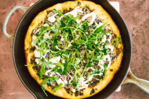 Crispy Seasoned Potato Pesto Pizza with Cashew Mozzarella Cream and Arugula on an Herbed Crust