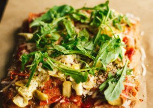 Salami, Artichoke, and Green Olive Pizza with Arugula on Focaccia